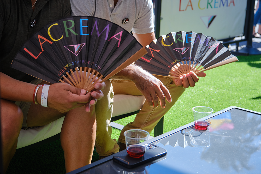 La Crema Pride celebration two glasses of pinot noir and two pride fans with la crema in rainbow