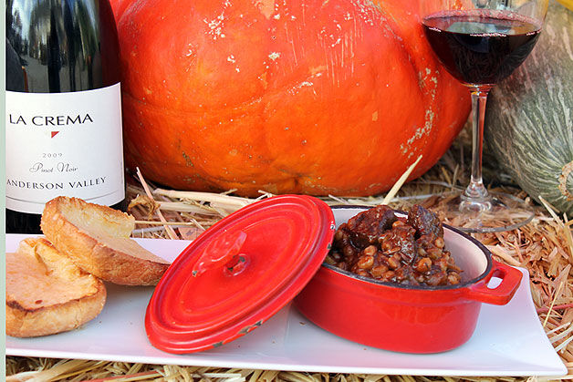 Beef stew in a pot with a glass of Pinot Noir