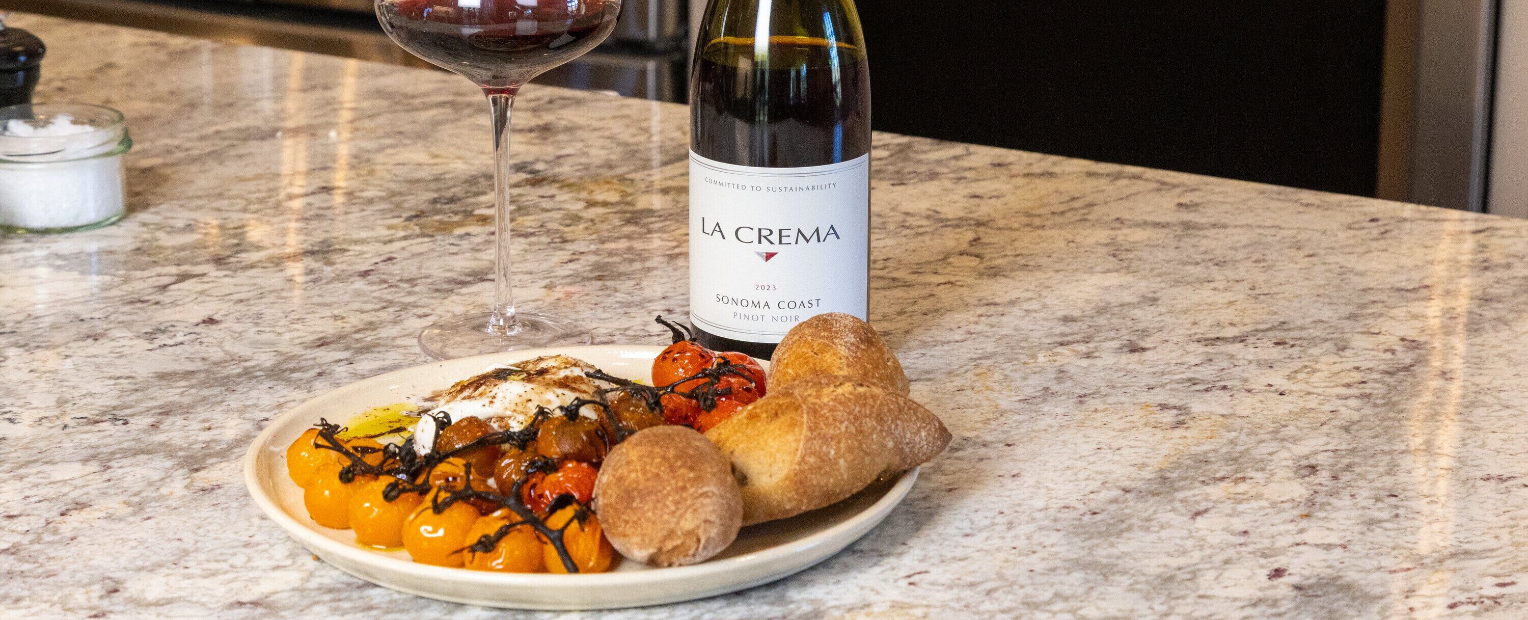 A plate of burata and blistered tomatoes with La Crema Pinot Noir