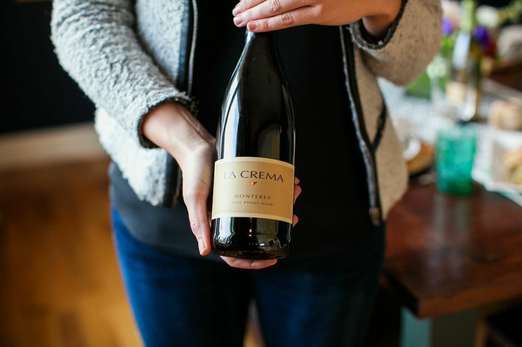 A person holding a bottle of La Crema Pinot Noir