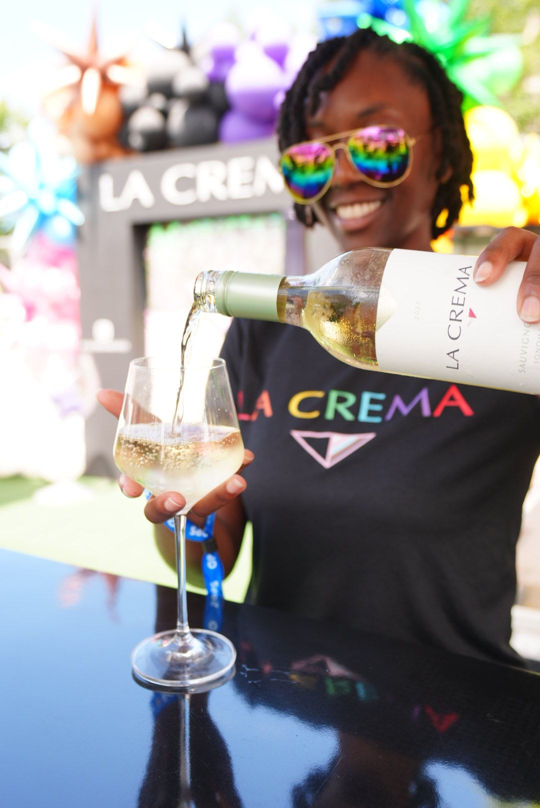 La Crema pride event women pouring a glass of sauvignon blanc