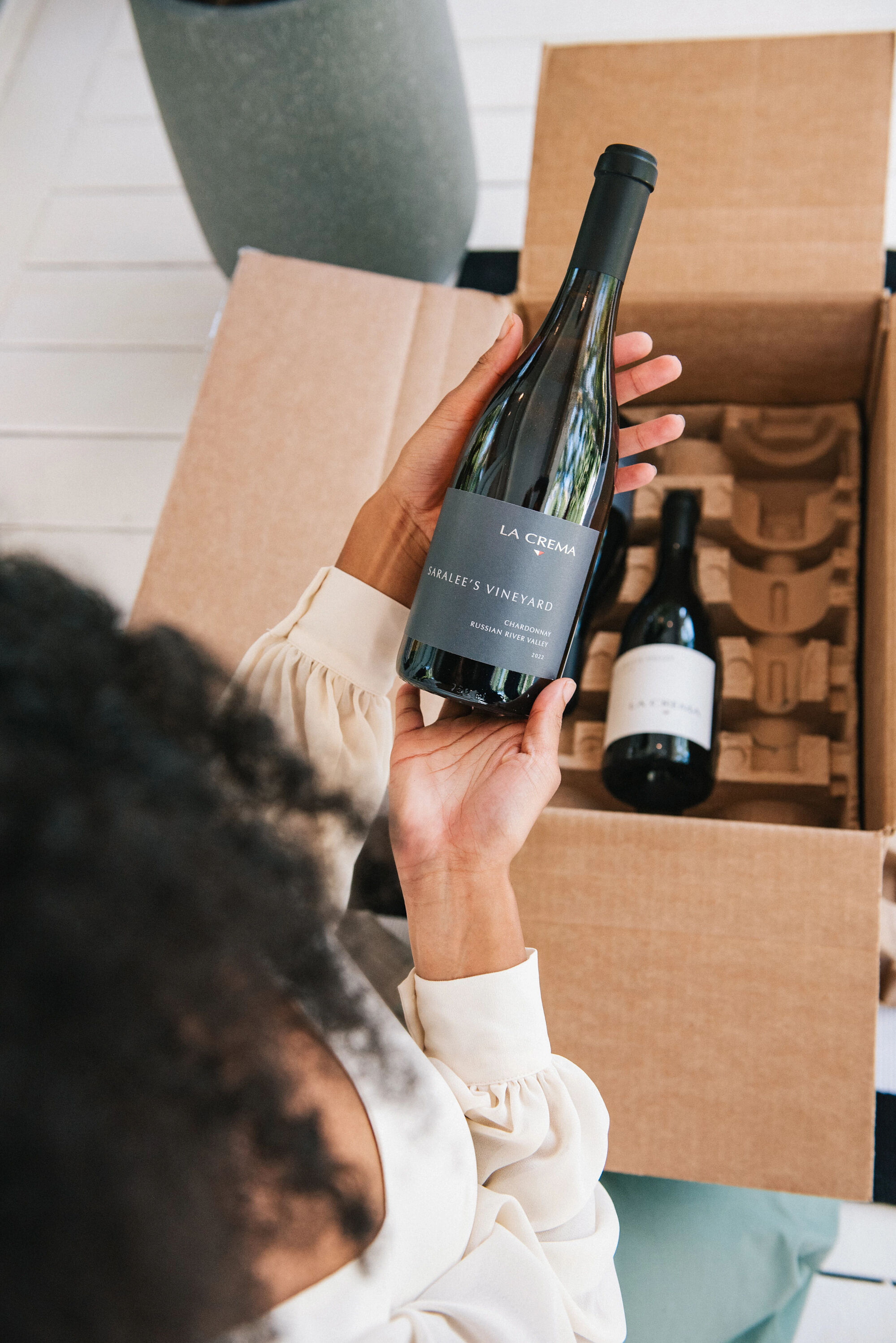 A person opening a wine club shipment from La Crema