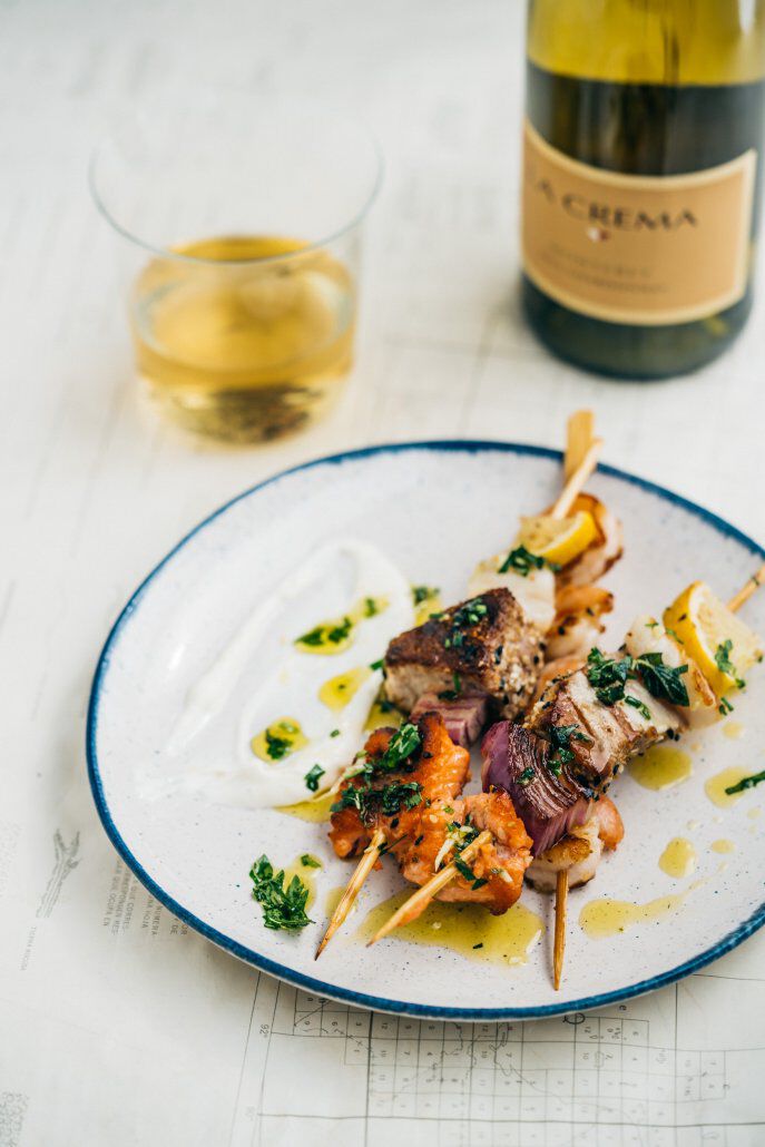 Seafood skewers on a plate with a glass of La Crema Chardonnay