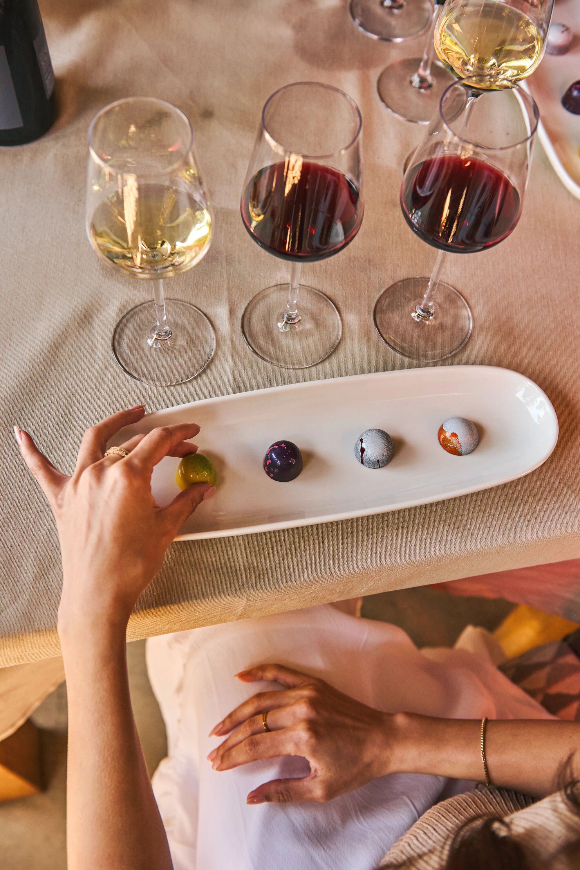 A person grabbing a piece of chocolate with their wine pairings