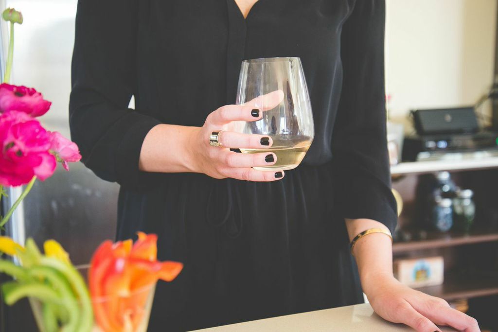 A person holding a glass of white wine