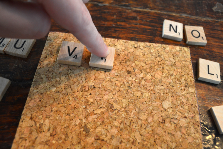 DIY Scrabble Coasters: Carefully place the words on the cork base with a daub of hot glue.