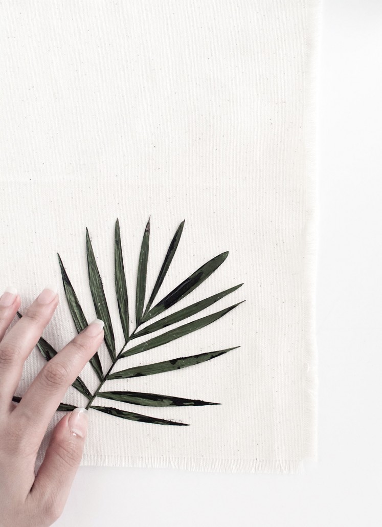 Press the painted palm leaf on the napkin to create DIY Palm Leaf Napkins