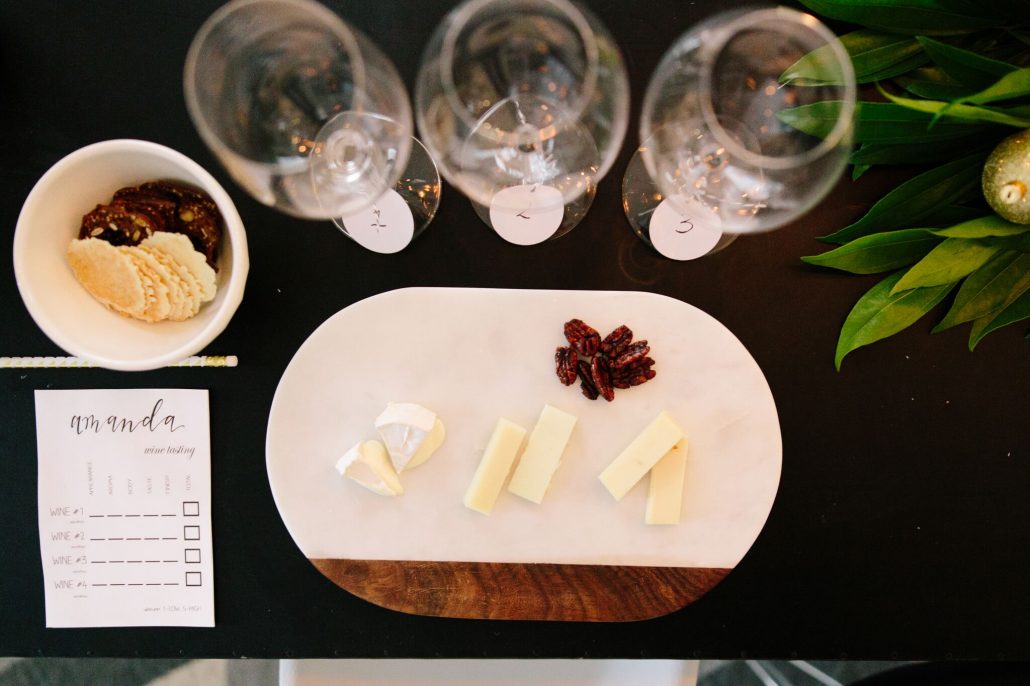 Cheese and accoutrement alongside numbered glasses for a blind wine tasting