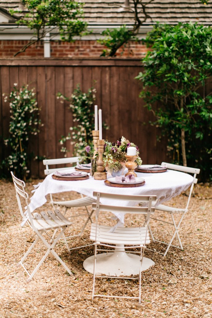 Folding table and chairs in a charming area of the backyard for a low-key dinner party by Camille Styles