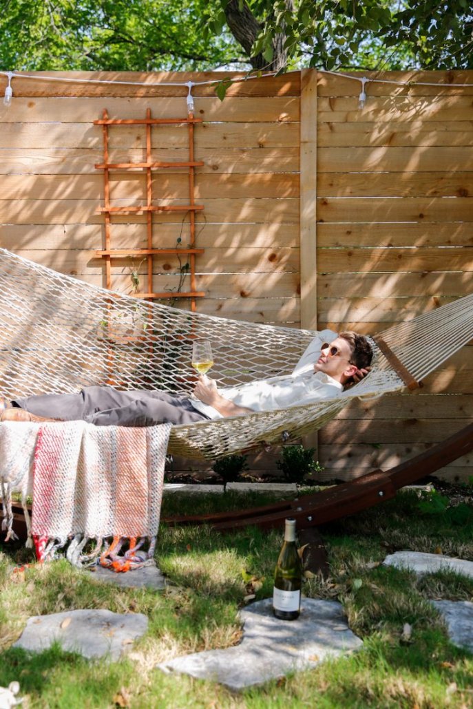 Man relaxing in a hammock next to a bottle of Chardonnay